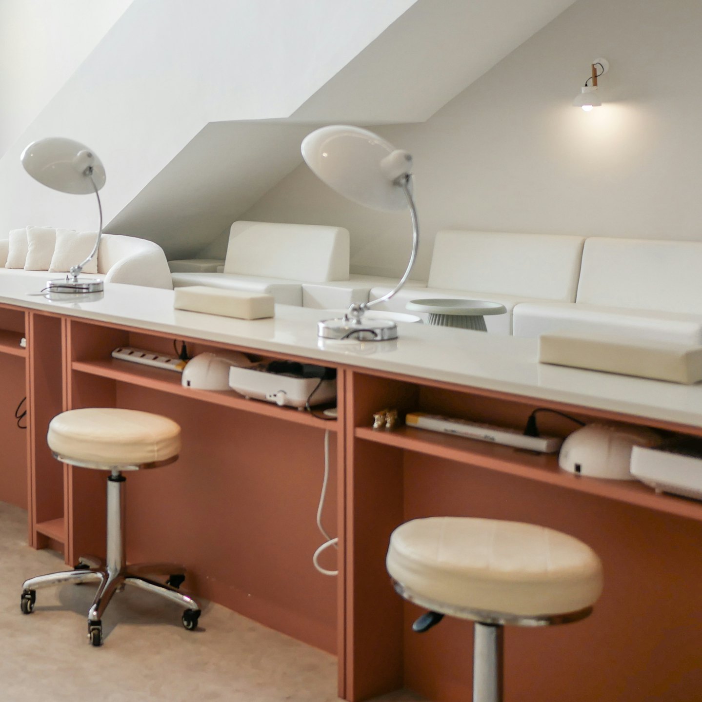 Due postazioni per manicure con banconi color pesca e lampade bianche.